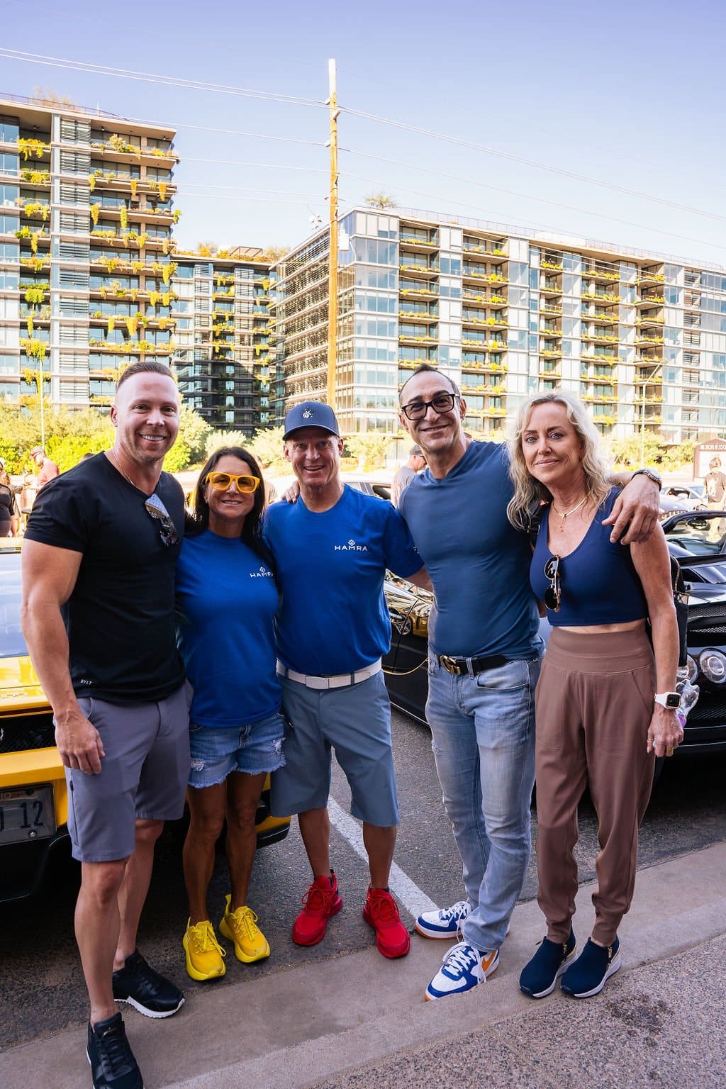 Five people posing together at Tires & Timepieces, with a yellow Lamborghini and a high-rise behind them