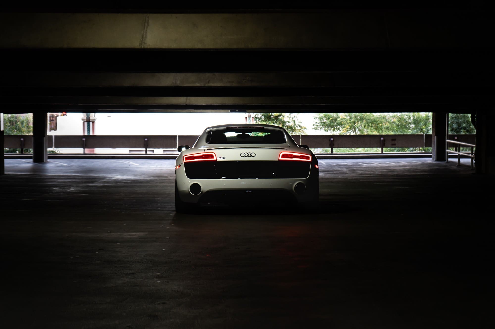 A white Audi R8 seen from behind at the mouth of a parking structure