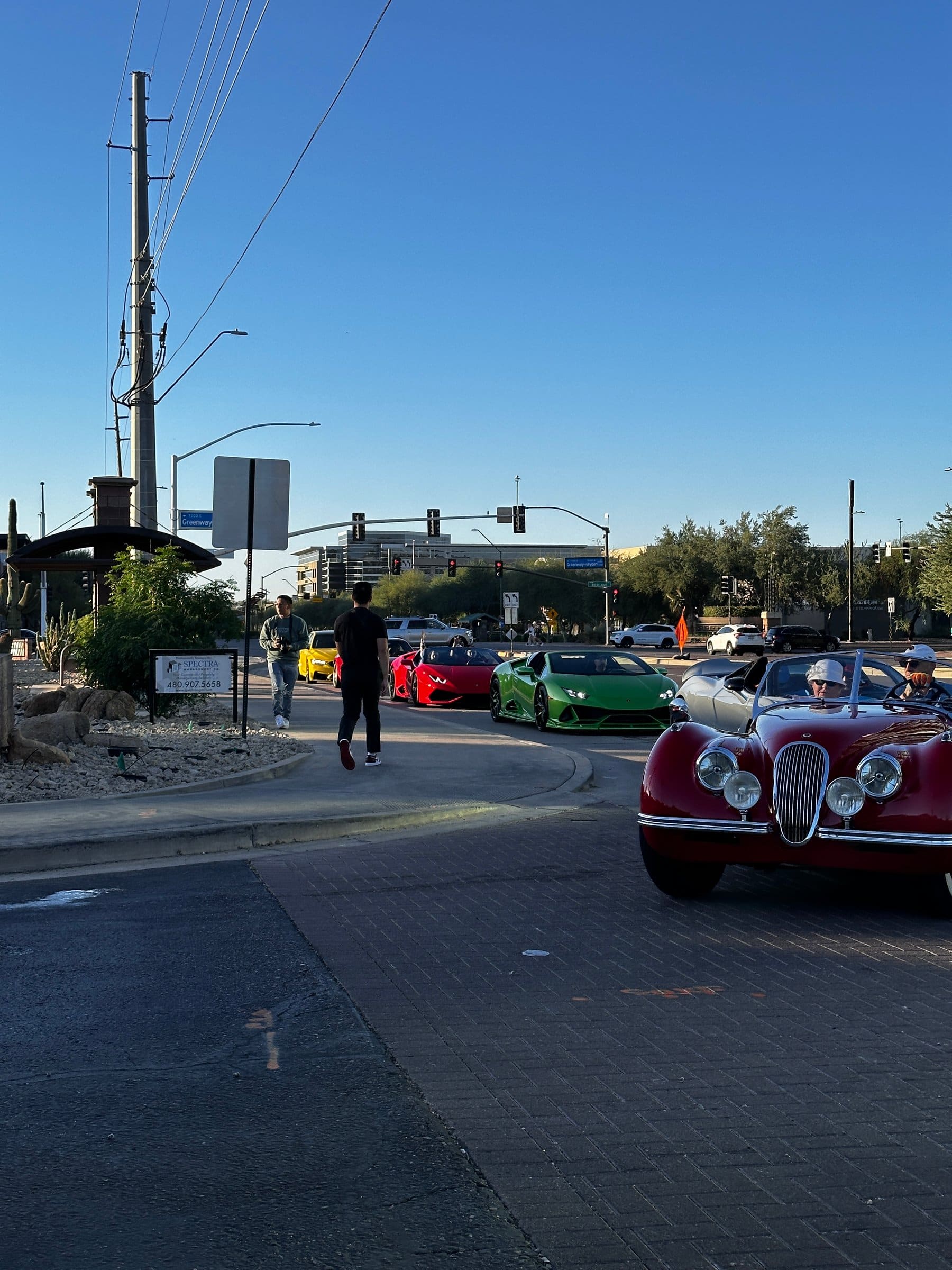 A green Lamborghini Huracan, a red Huracan and a vintage Jaguar XK at a Scottsdale intersection
