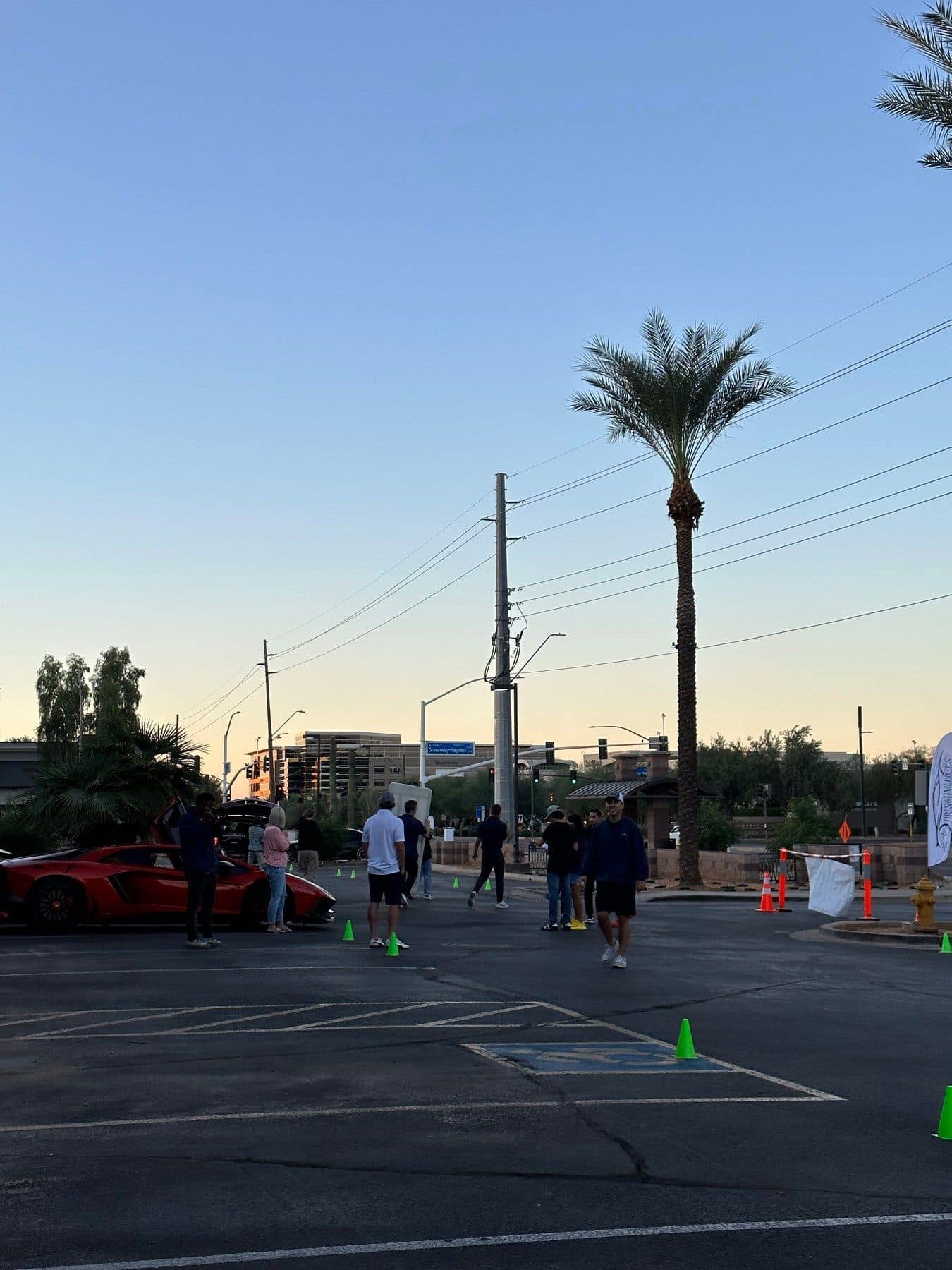 A red Lamborghini and guests on a Scottsdale street at Tires & Timepieces, palm trees behind