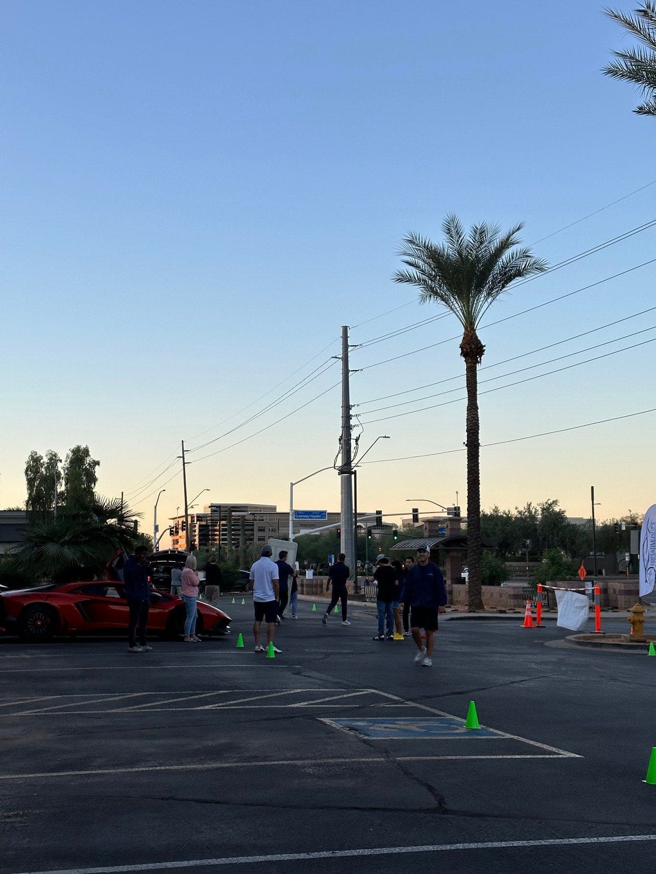 A red Lamborghini and guests on a Scottsdale street at Tires & Timepieces, palm trees behind